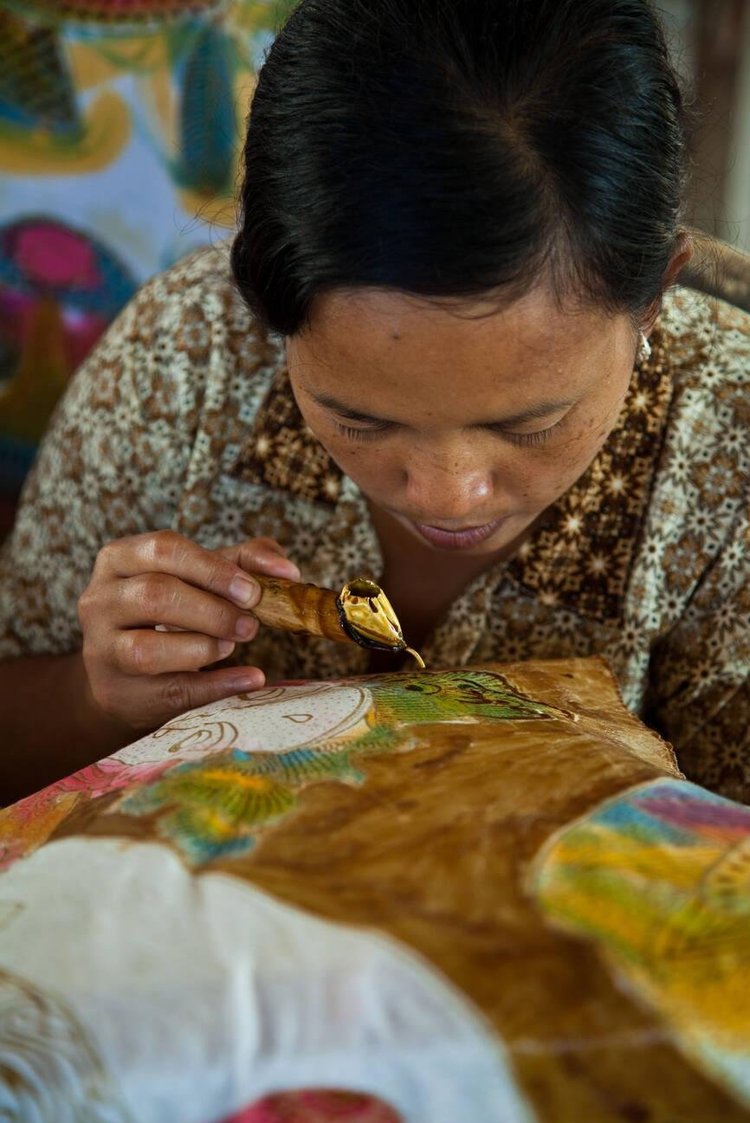 An Indonesian woman uses a tradition dyeing method for creating a batik print